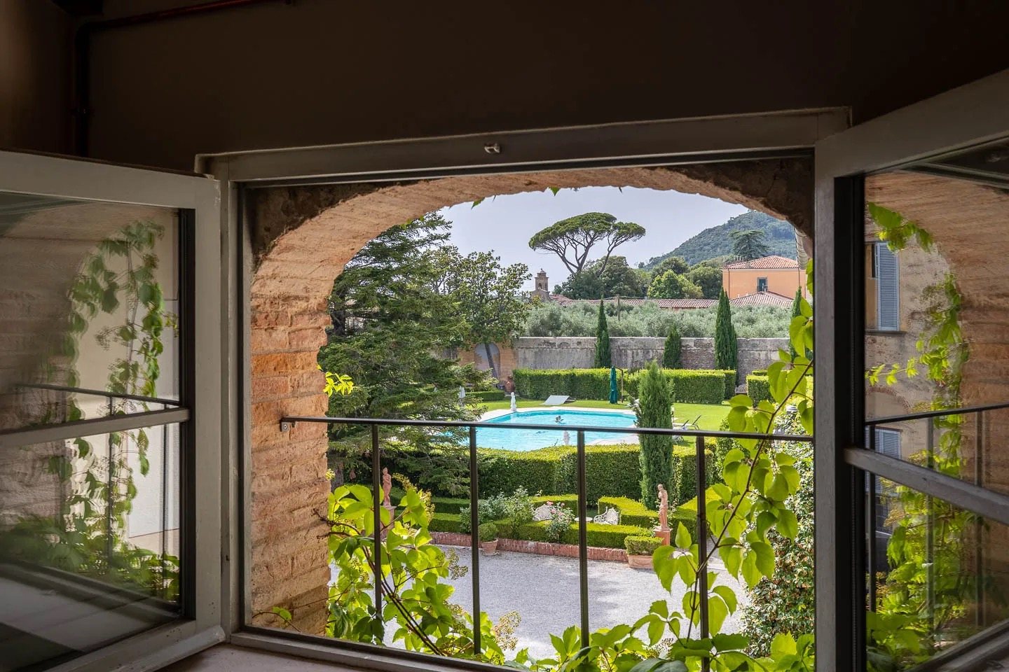 Looking out through a brick arch to the garden, the pool and the hills beyond